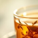 Tulsi tea steeping in a glass pot with herbs floating